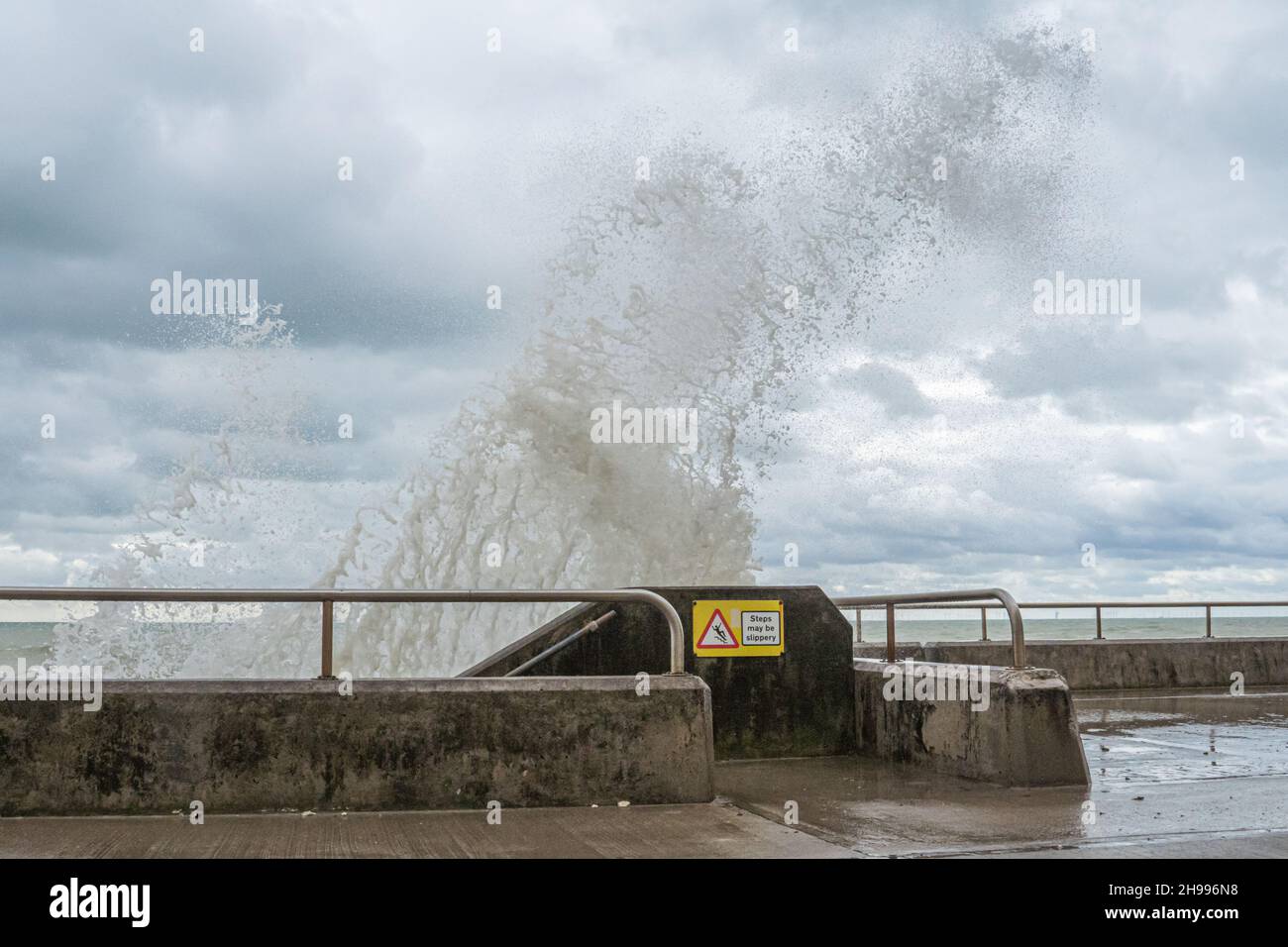 Steps maybe slippery sign as rough seas pound the under cliff walk between Brighton and Saltdean. Stock Photo