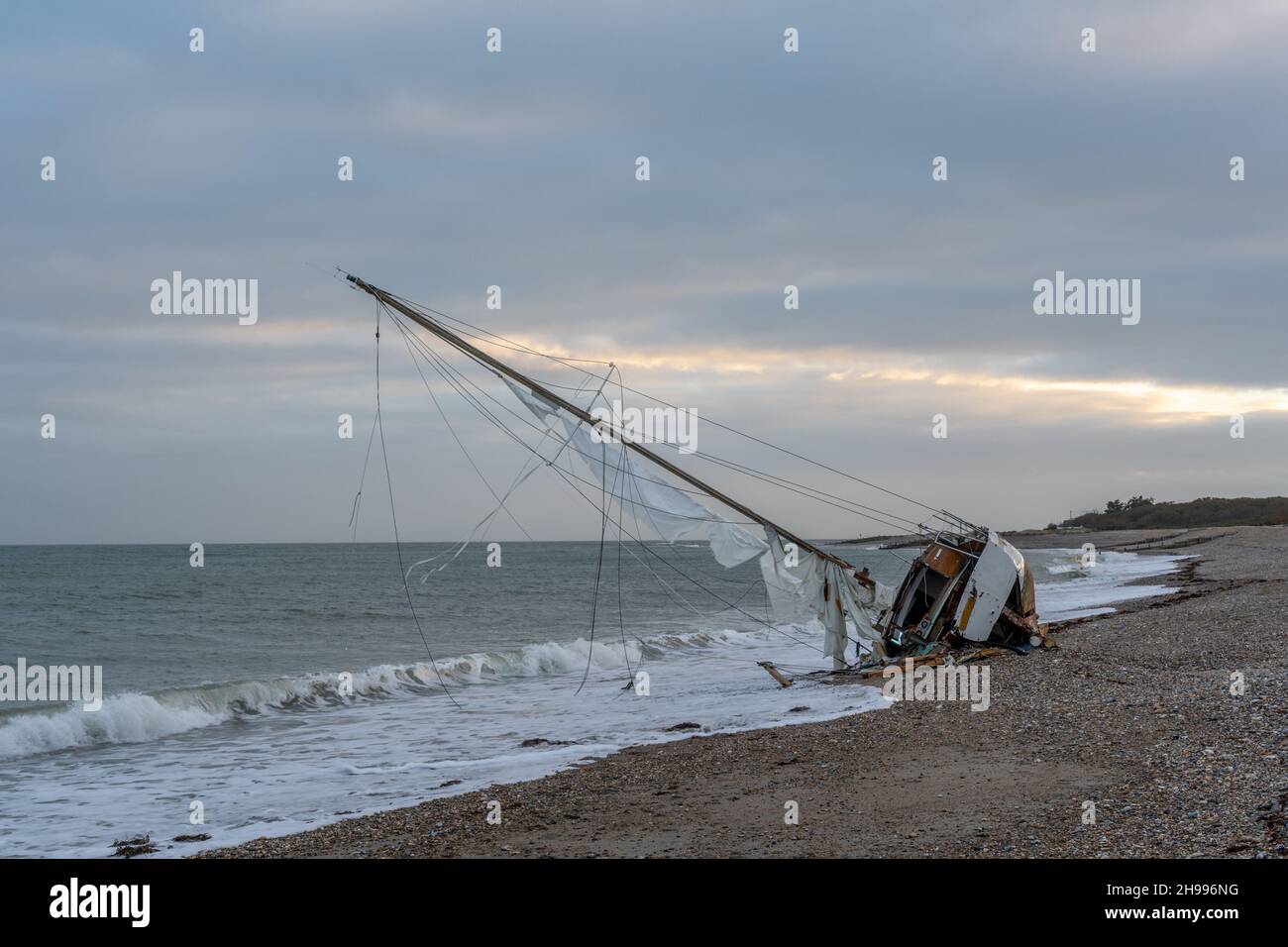 Abandoned and shipwrecked sailing boat aground on the beach at Church Norton between Pagham and Selsey near Chichester in West Sussex. Stock Photo