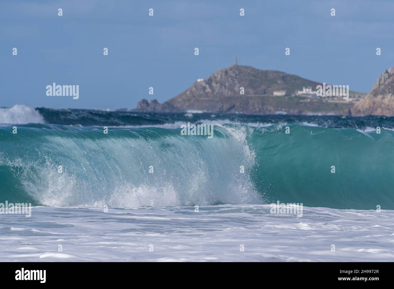 Emerald green surf on Sennen Cove beach in western Cornwall with Cape Cornwall in the distance. Stock Photo