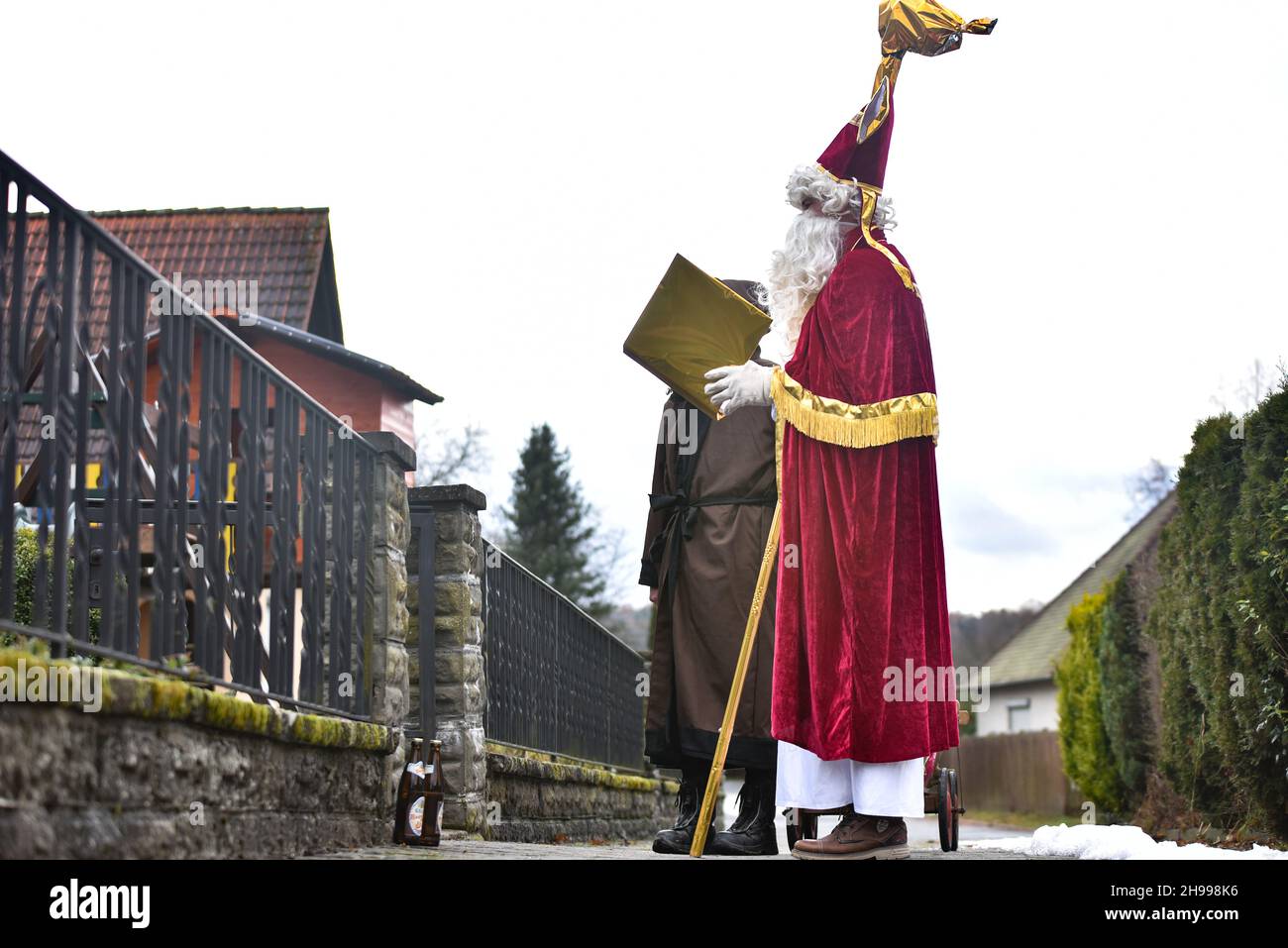 Germany ,Kirchlauter,  - 05 Dec 2021 - Local News - St. Nikolaus fundraiser for Franken Hospice Bamberg    Image: Markus Geier (Nikolaus) and Jan Schneiderbanger (Knecht Ruprecht) walk around the town of Kirchlauter, dressed as the Christmas pair, delivering goodies to children along a registered route. Those taking part donate money, 100% of the money is sent to a youth hospice in Bamberg, Germany. Stock Photo