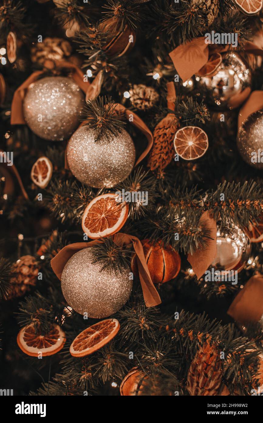 Creative Christmas tree decorated with dry oranges, pine cones, golden balls. Magic cozy details, winter season, holiday eve Stock Photo