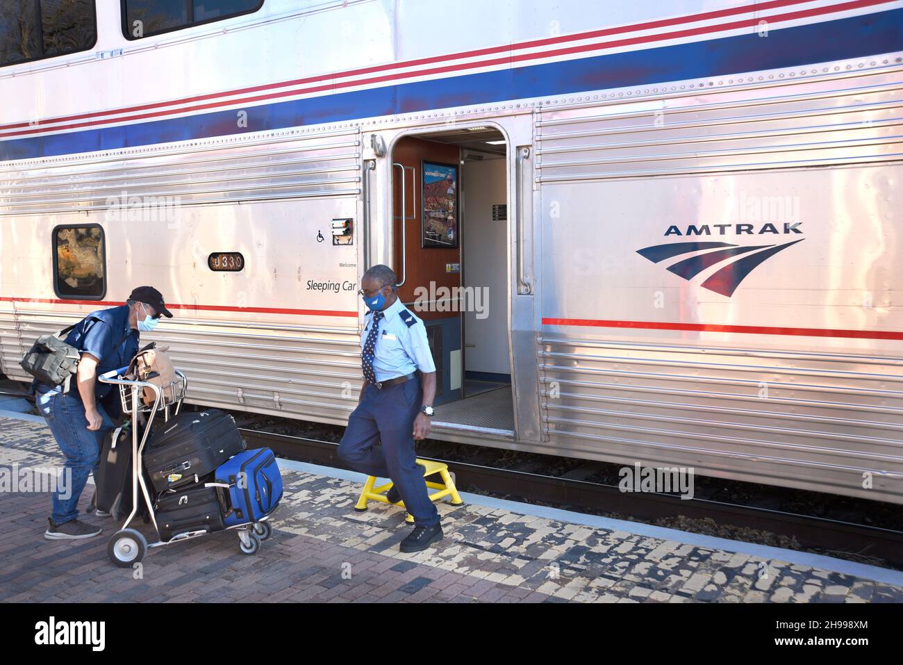 An Amtrak conductor in Lamy, New Mexico, loads luggage into the Southwest Chief passenger train which runs between Chicago and Los Angeles. Stock Photo