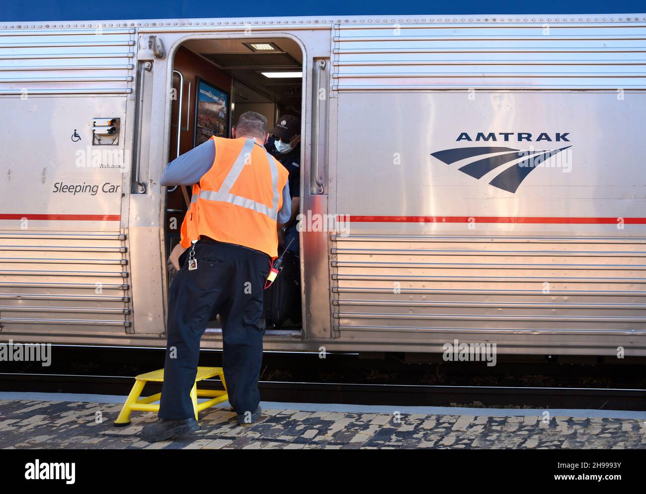 An Amtrak employee in Lamy, New Mexico, loads luggage into the Southwest Chief passenger train which runs between Chicago and Los Angeles. Stock Photo