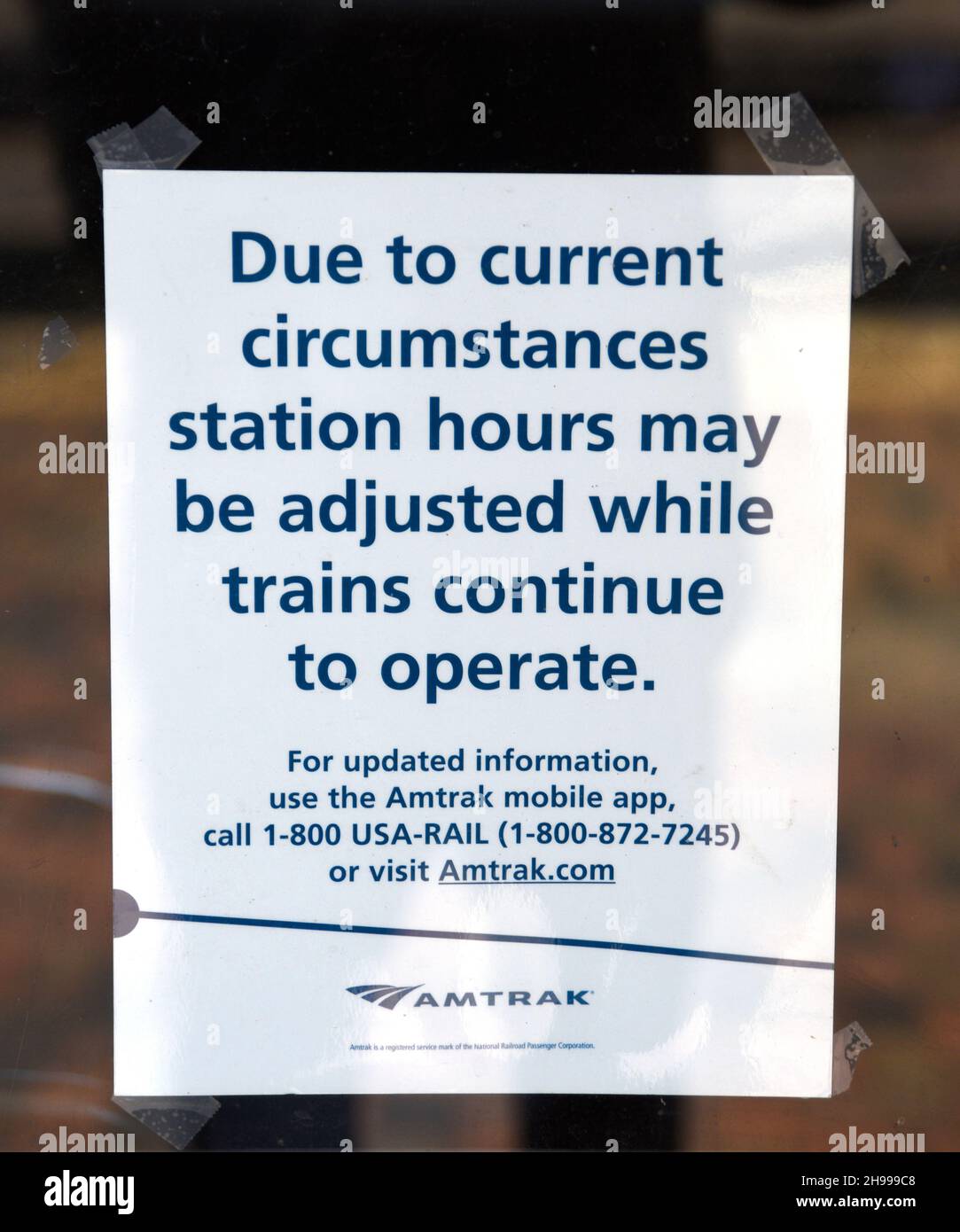 A sign posted on the door of the Amtrak train station in Lamy, New Mexico, advises of possible service changes caused by the pandemic. Stock Photo