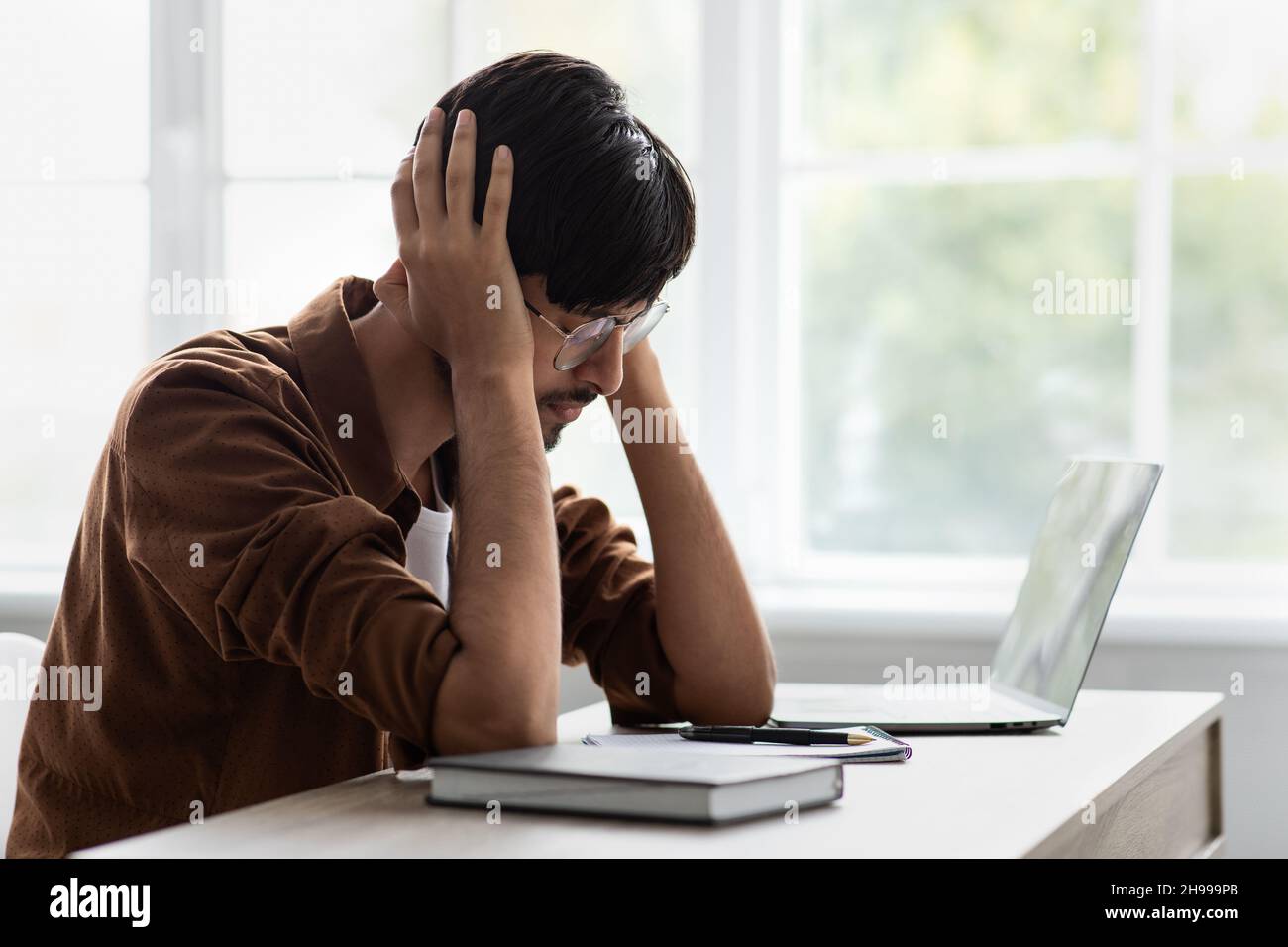 Sad middle eastern man suffering from headache at office Stock Photo