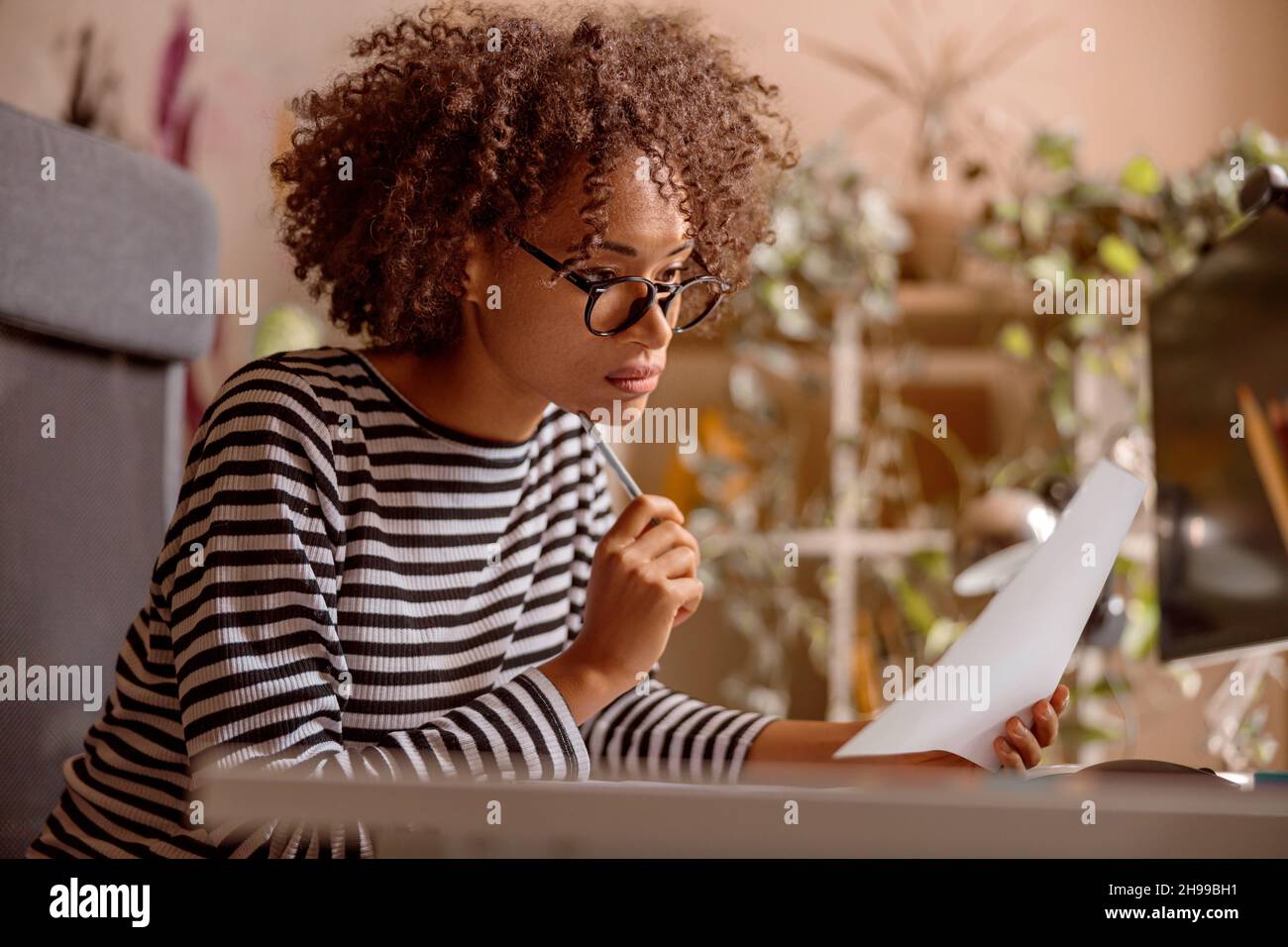 Multiracial woman is working on project at home Stock Photo