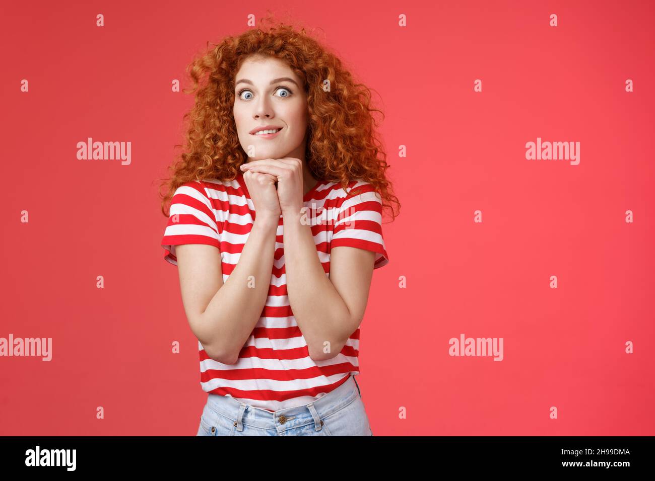 Excited thrilled young impulsive good-looking redhead female stare camera express desire aspiration smiling crazy hold hands chin pressed keep herself Stock Photo