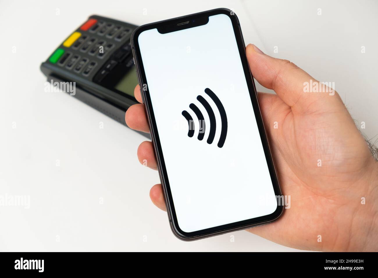 Contactless payment for online shopping with wireless POS payment terminal on the background. Man holding a mobile phone with app for payment. November 2021, San Francisco, USA Stock Photo