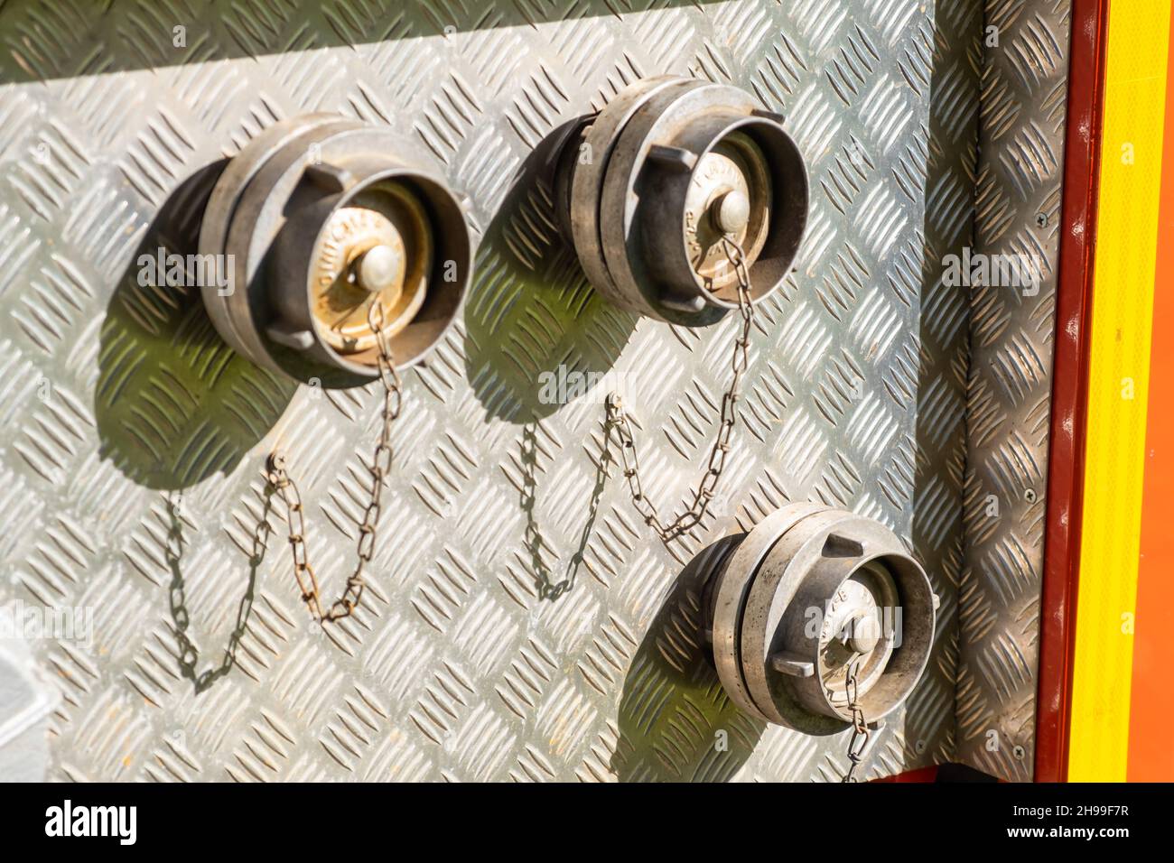 Closed with corks hose plugs on grey metal side of contemporary fire truck standing at station on sunny day extreme close view Stock Photo