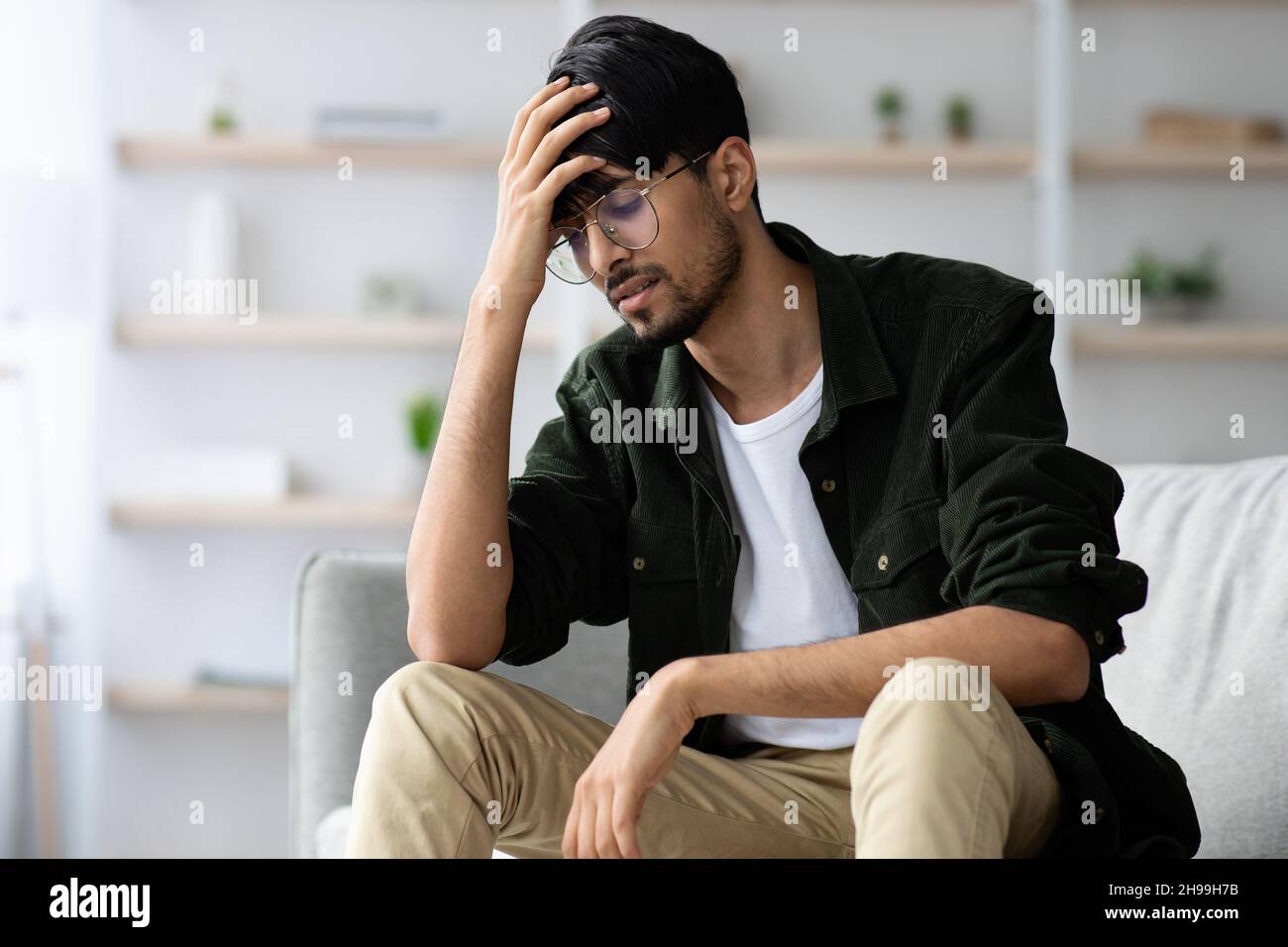 Indian guy touching his head, suffering from headache, copy space Stock Photo