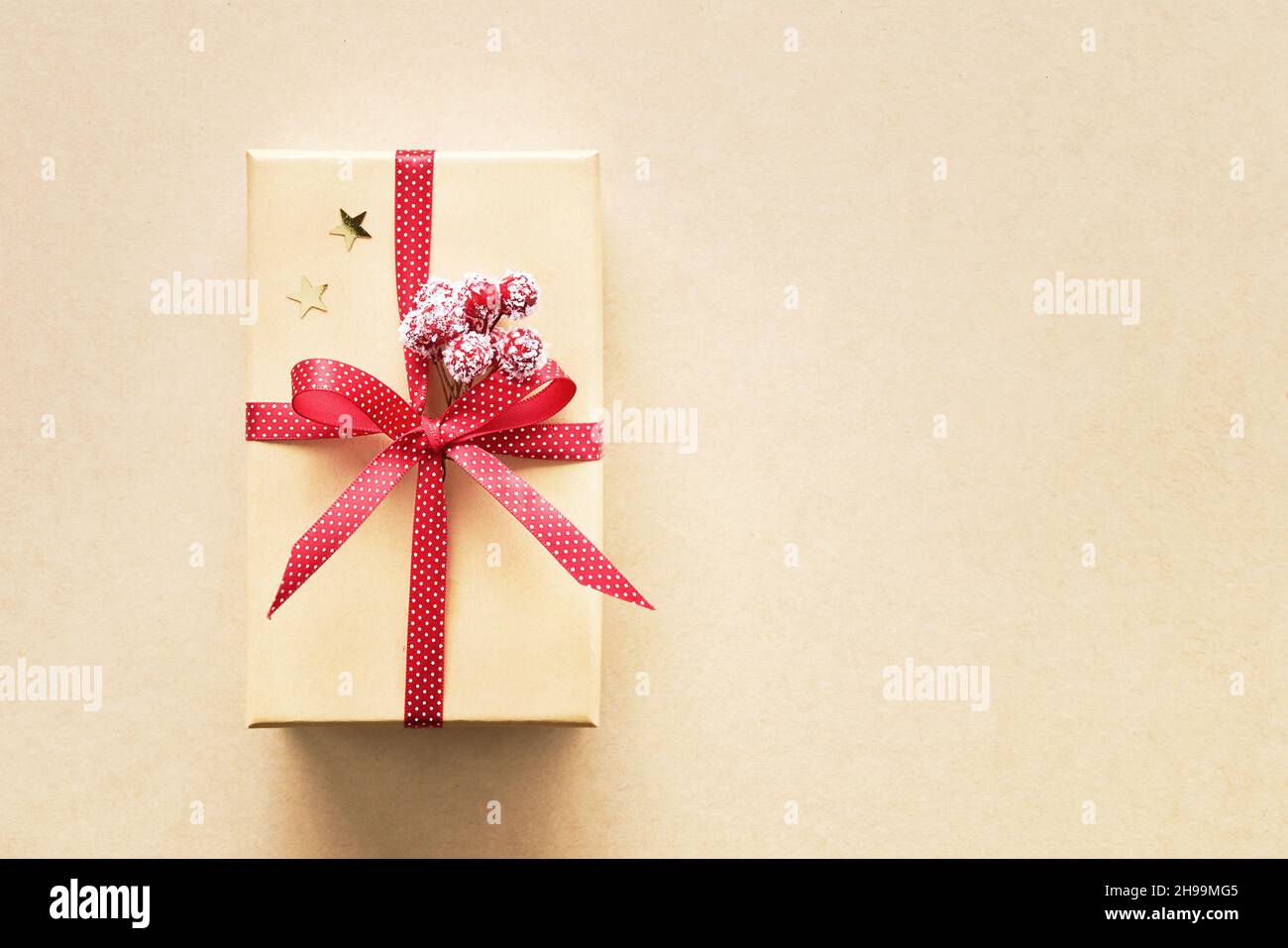 Christmas gift box with decoration on a craft paper background. Top view, copy space for text Stock Photo