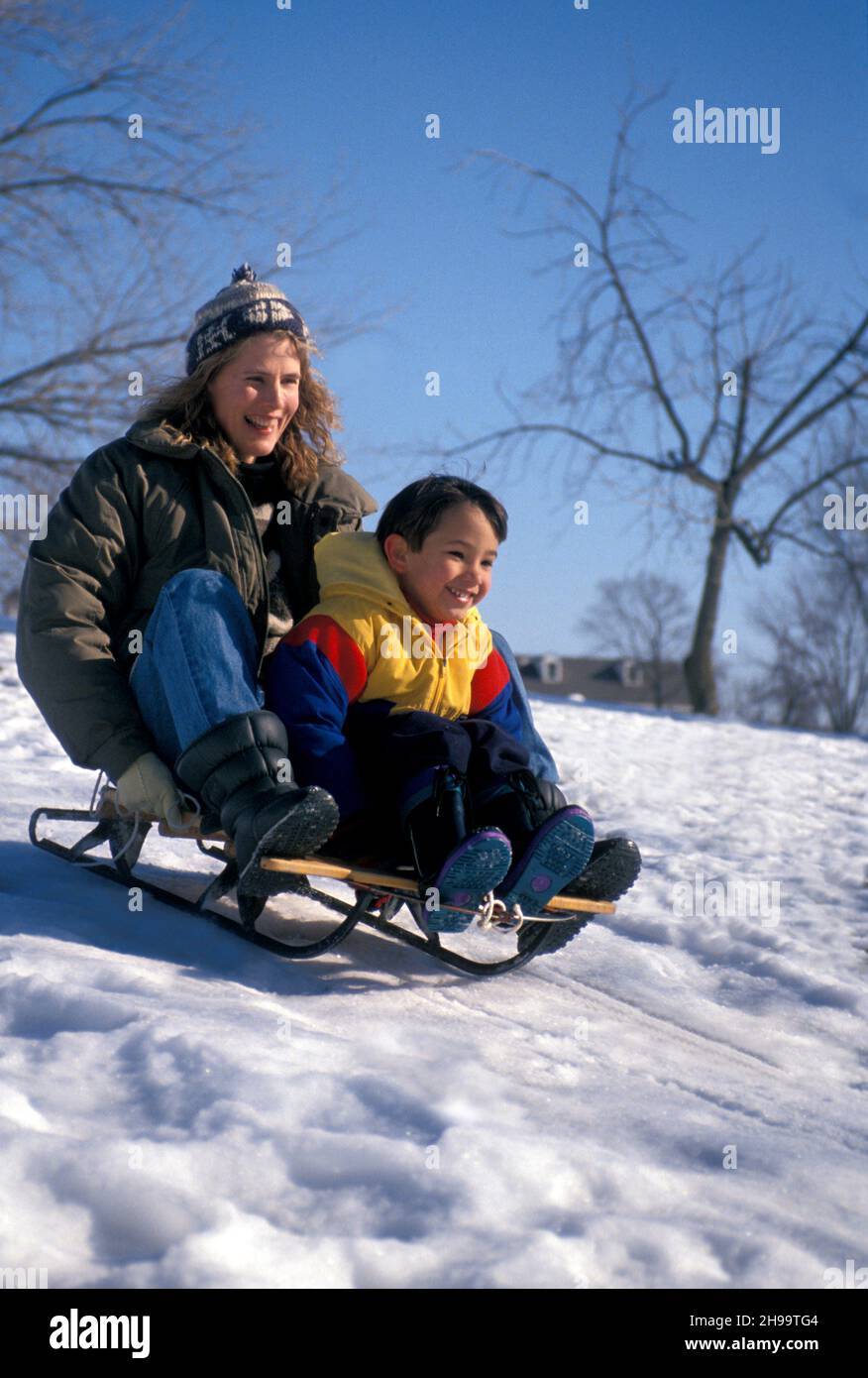 Mother and son starting off down the hill tandem on an old wooden sled, Missouri, USA Stock Photo