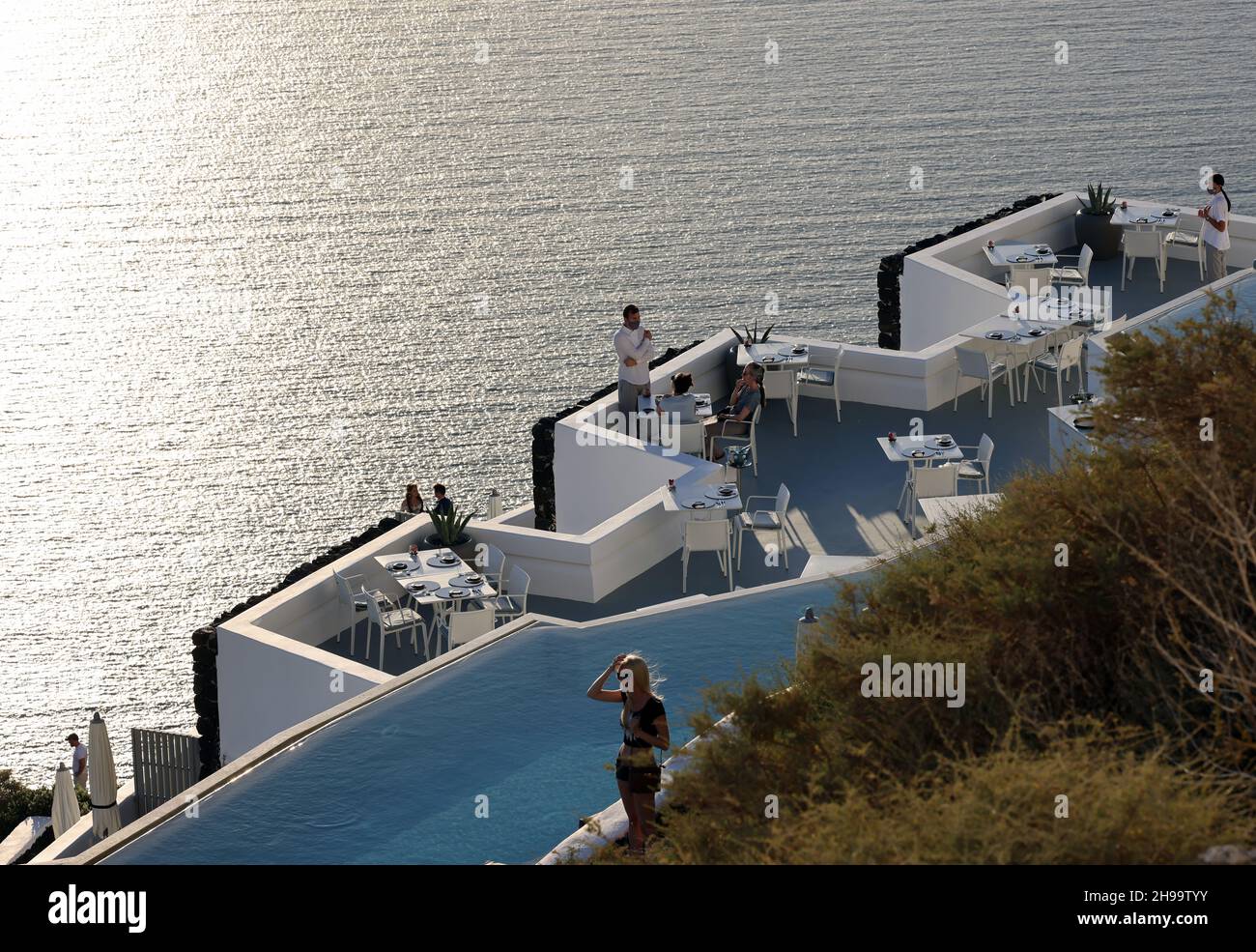 Imerovigli, Santorini, Greece - June 29, 2021: Tables on the restaurant terrace with a picturesque view of the sunset in Imerovigli. Santorini, Greece Stock Photo