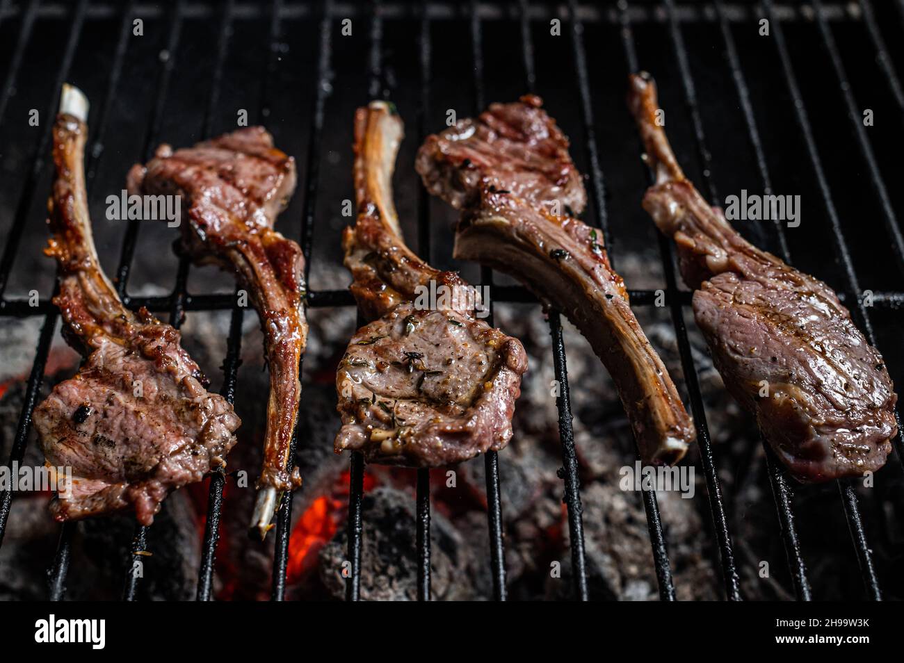 Grilled lamb mutton chop steaks on barbecue, outdoor BBQ grill with ...