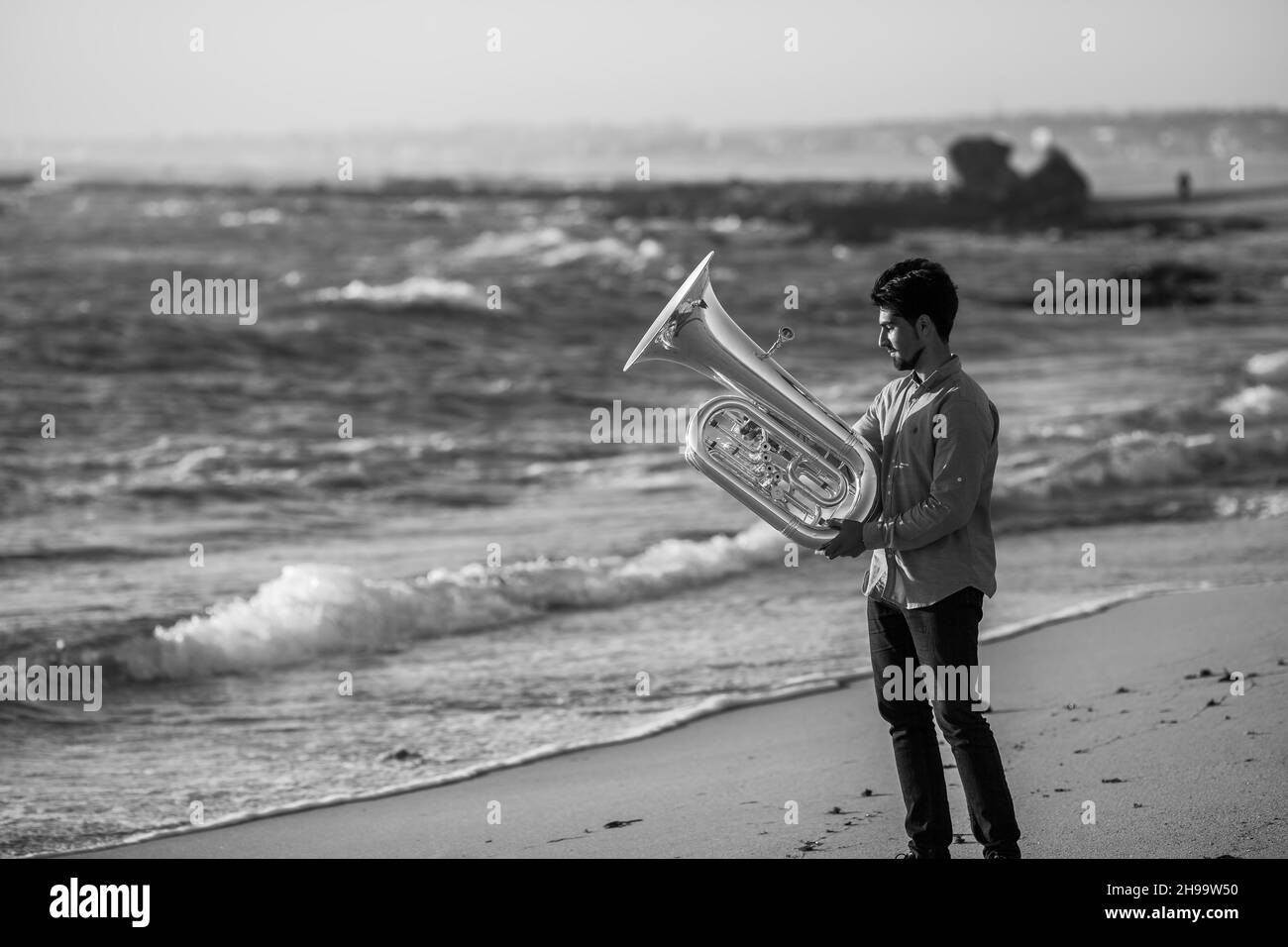 Musician with a tuba near the ocean. Black and white photo. Stock Photo