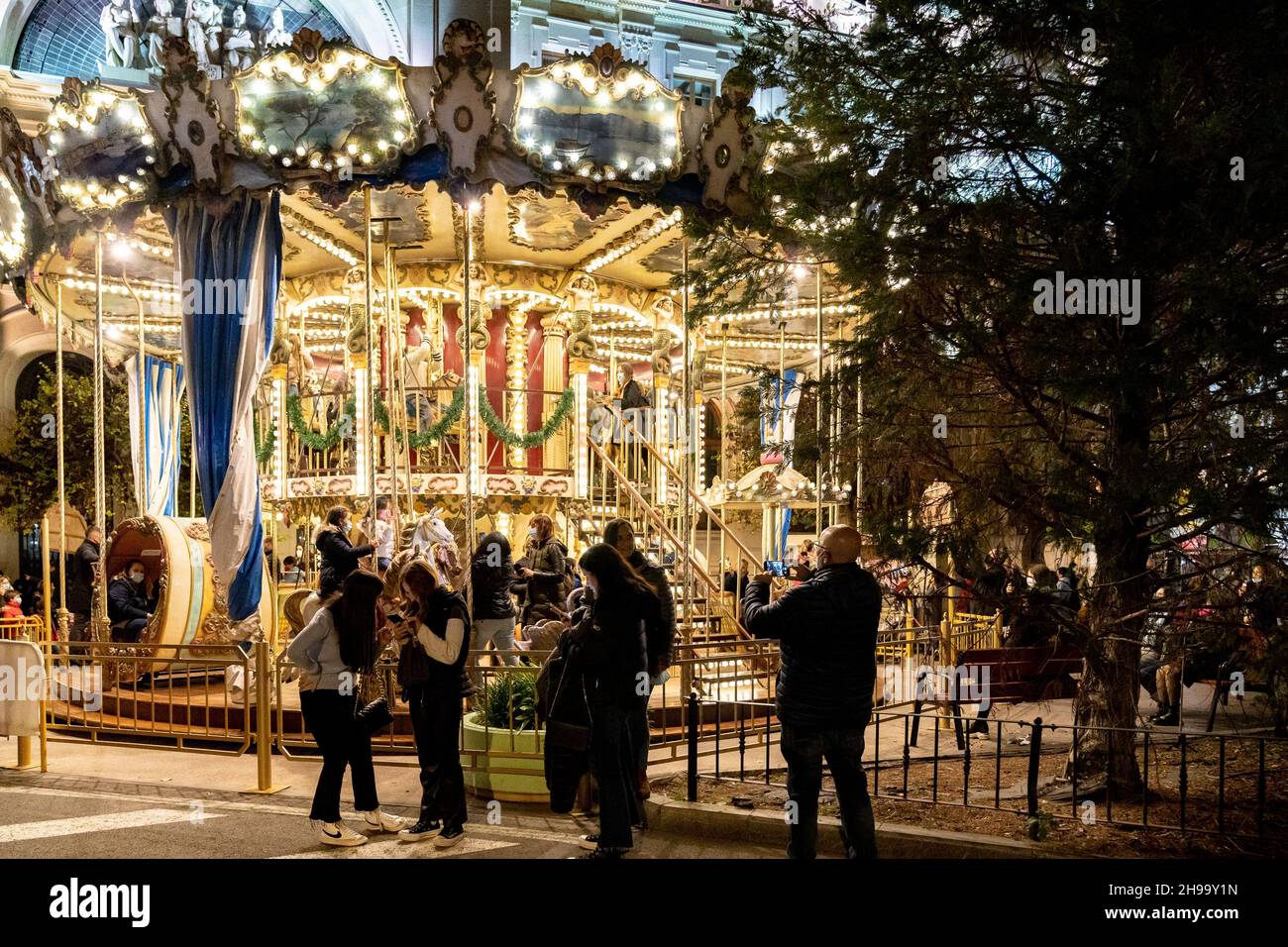 Valencia, Spain. 04th Dec, 2021. People take photos at the carousel in Valencia's Town Hall Square.Valencia welcomes Christmas with the classic lights. Two giant balls, 14 and 11 meters high, have begun to shine in the Town Hall Square with moving lighting, music, and an audiovisual show that can be seen every hour. The adjacent streets have also released Christmas decorations. (Photo by Xisco Navarro/SOPA Images/Sipa USA) Credit: Sipa USA/Alamy Live News Stock Photo