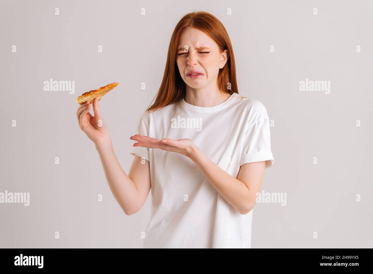 Studio portrait of sick young woman closed eyes feeling pain in stomach after eating pizza