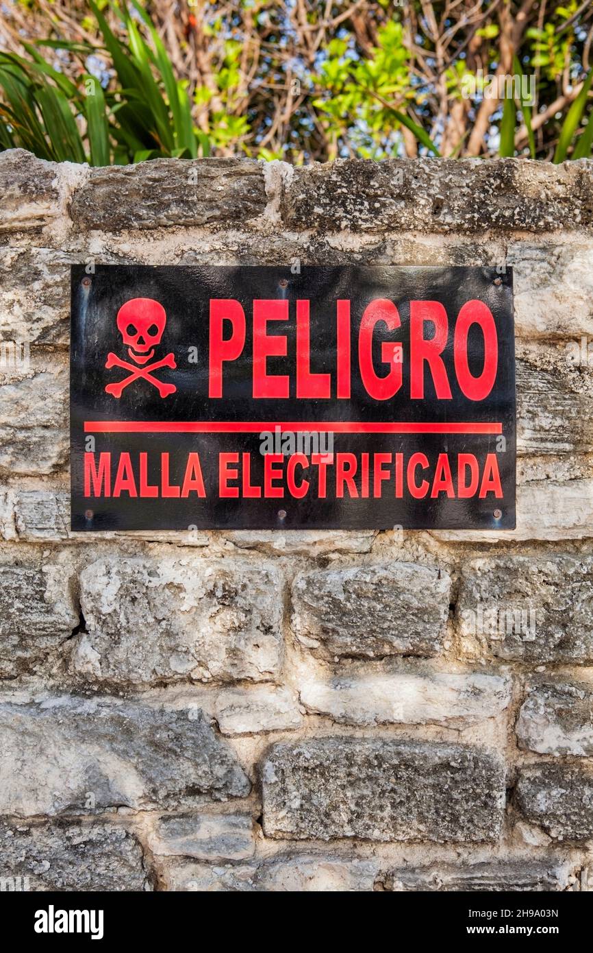 Danger sign in Spanish on a stone wall in Cancun, Electricity supply