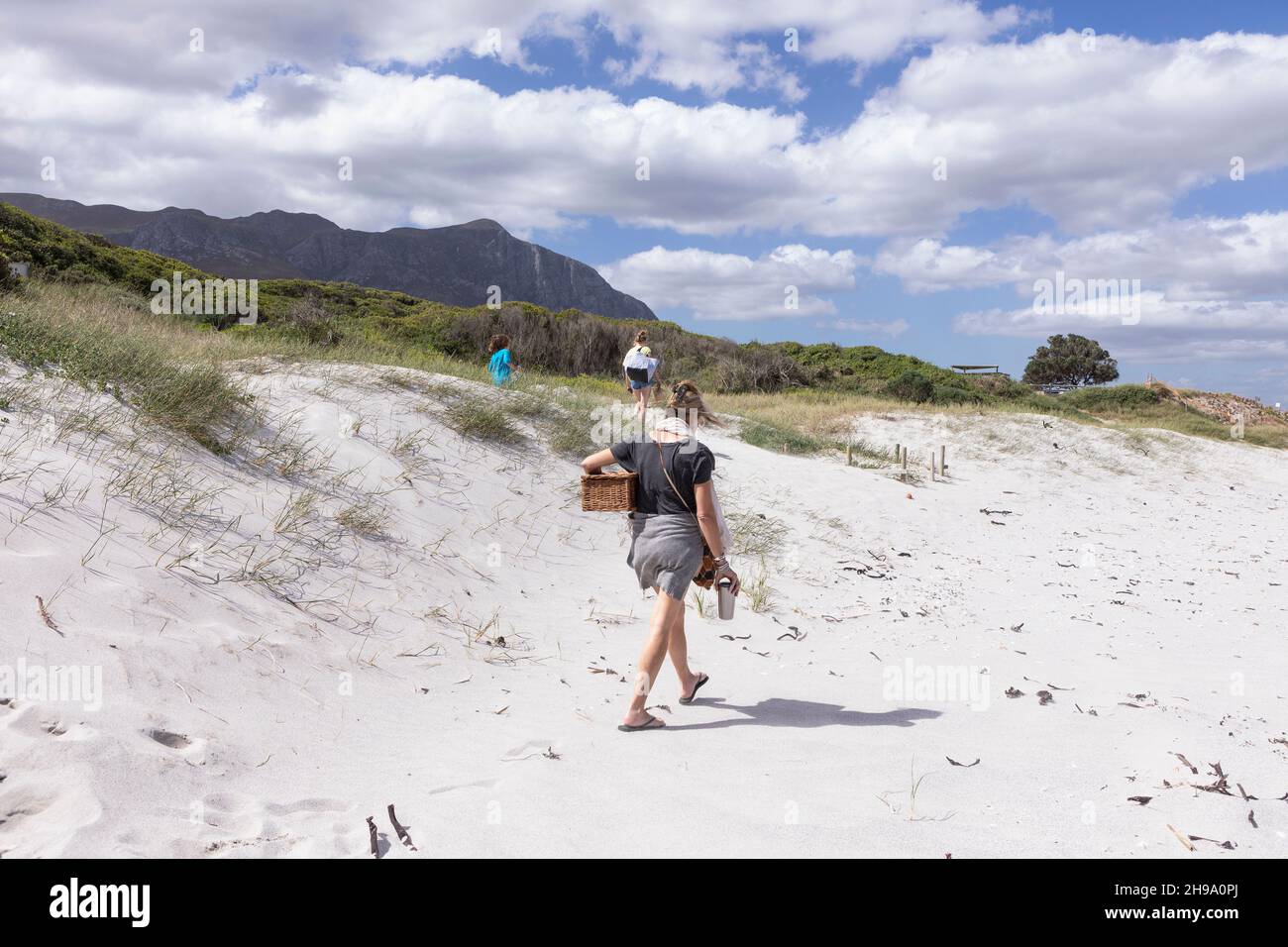 Adult woman carrying picnic basket on Grotto Beach, Hermanus, Western Cape, South Africa. Stock Photo
