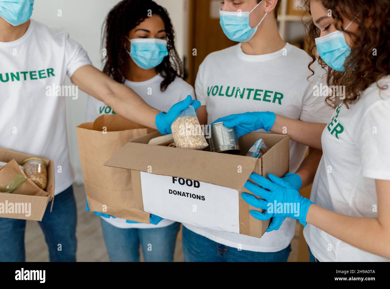 International group of young volunteers sorting donated food in boxes, working in charity donation center, closeup Stock Photo