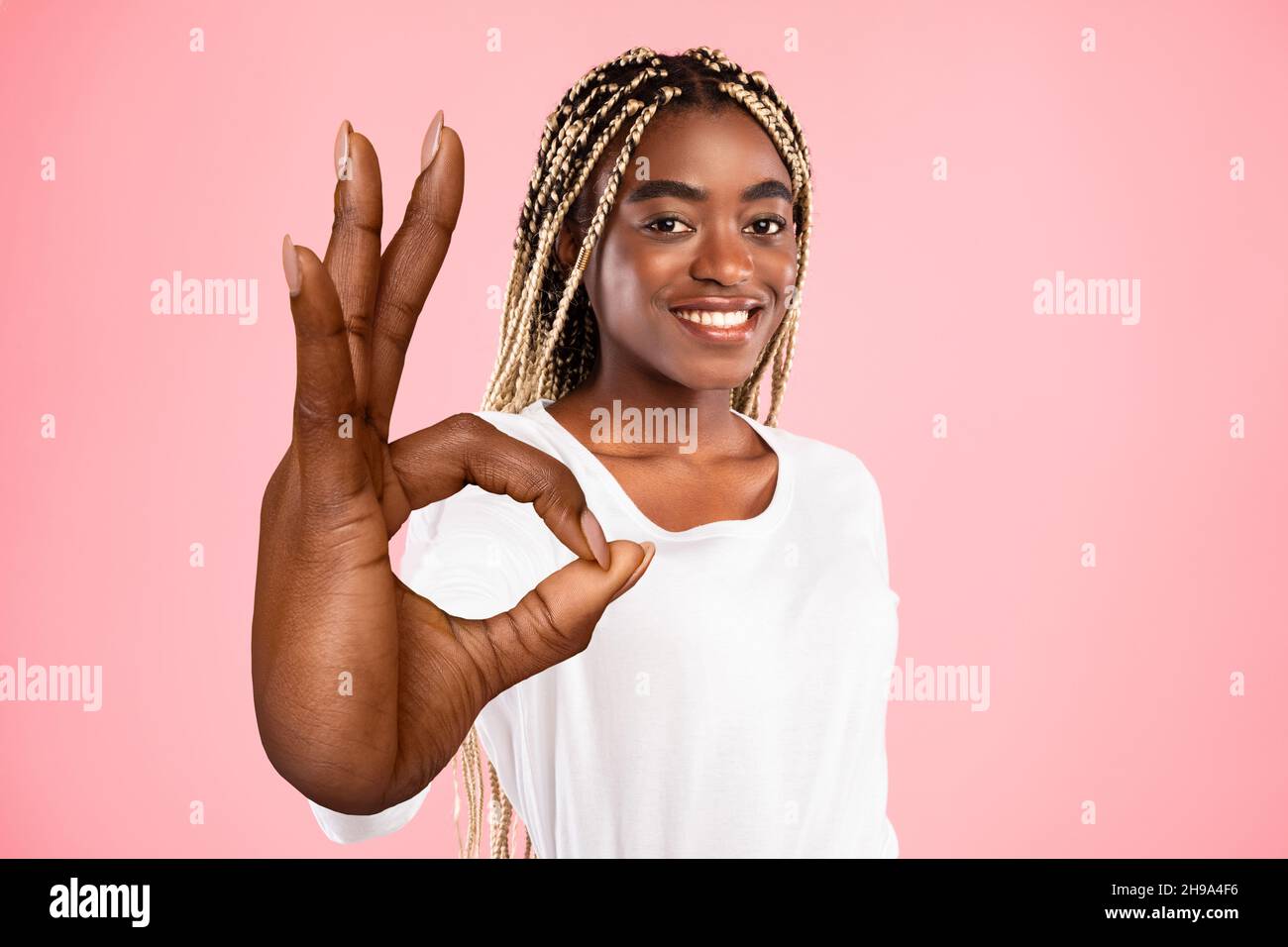 Beautiful young black woman showing big OKAY gesture on pink studio ...