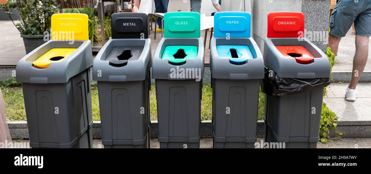 Row of many different multicolored plastic waste cans for garbage sorting and recycling at city street outdoors. Environmental protection and nature Stock Photo