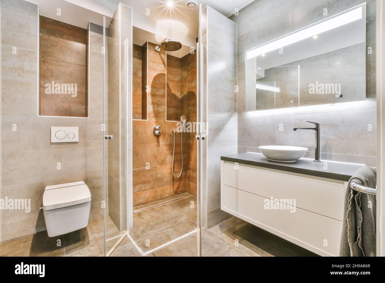 Flush toilet and shower cabin with glass partition in washroom at home Stock Photo