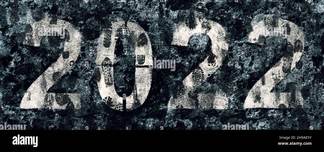 Numbers 2022 painted on asphalt covered with dirty footprints on melted snow Stock Photo