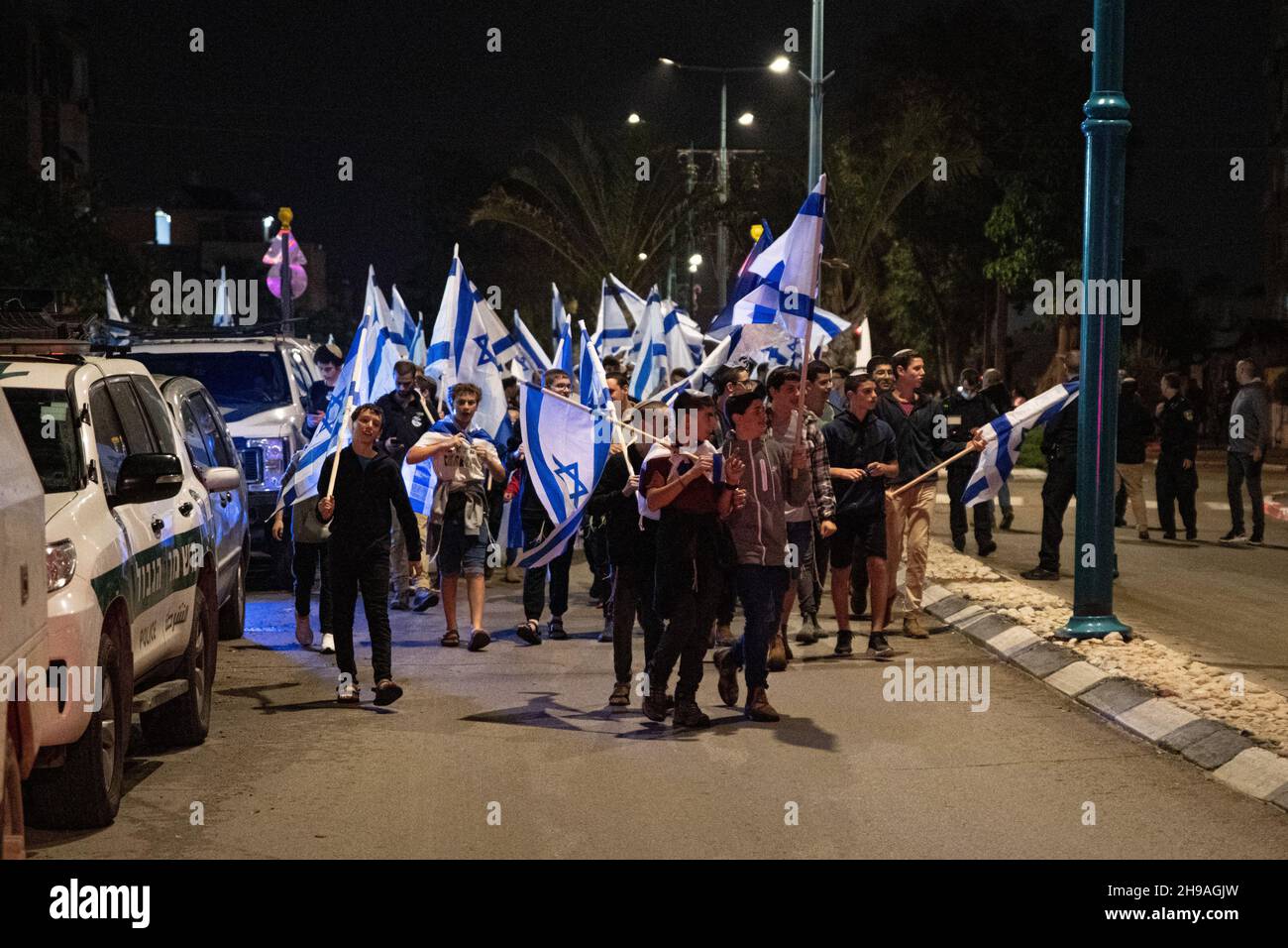 Lod, Israel. Dec 5th 2021, Israeli religious right wing public marches with flags through the mixed city of Lod, celebrating the last candle of the holiday of Hanukkah. The event was organized by religious zionist groups, some of them percived as radical in Israel, aiming to expand the jewish present within the country. The city of Lod is populated by both Jewish and Muslim, which used to live in peace until the arrival of a “Torah Nucleus” into the city. Credit: Matan Golan/Alamy Live News Stock Photo