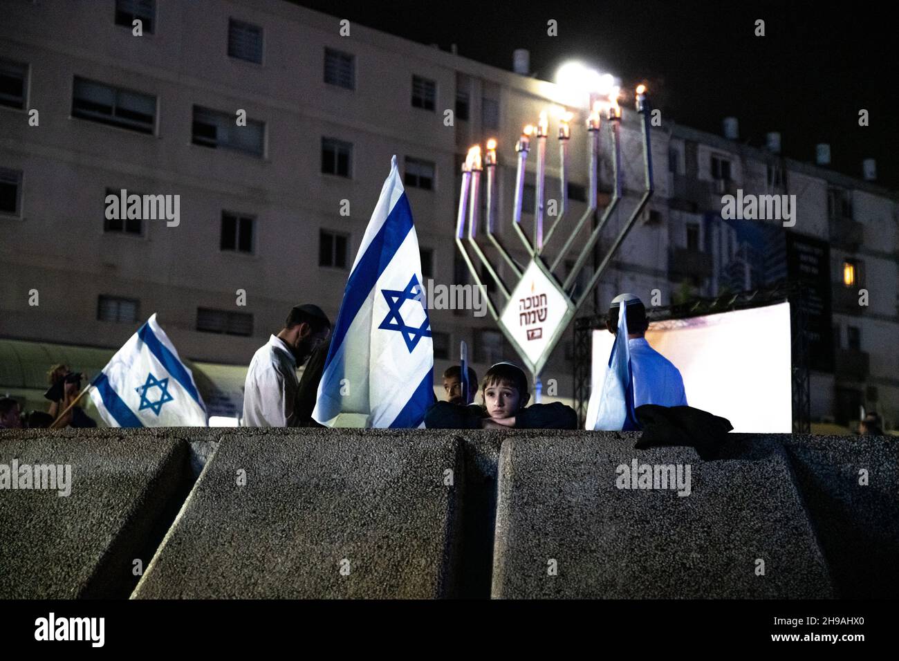 Lod, Israel. Dec 5th 2021, Israeli religious right wing public marches with flags through the mixed city of Lod, celebrating the last candle of the holiday of Hanukkah. The event was organized by religious zionist groups, some of them percived as radical in Israel, aiming to expand the jewish present within the country. The city of Lod is populated by both Jewish and Muslim, which used to live in peace until the arrival of a “Torah Nucleus” into the city. Credit: Matan Golan/Alamy Live News Stock Photo