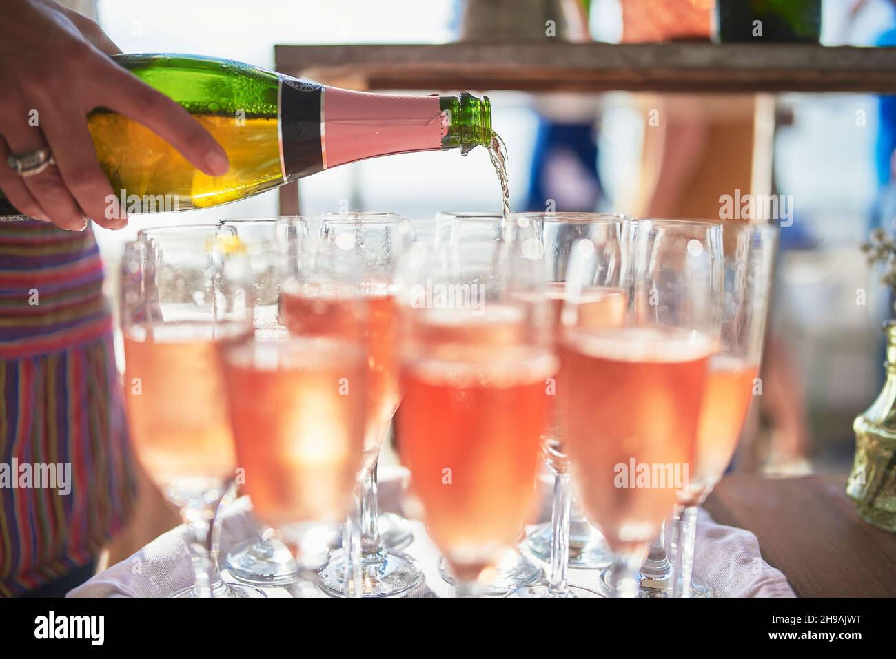 Closeup shot of a female pouring rose into a bunch of champagne glasses ...