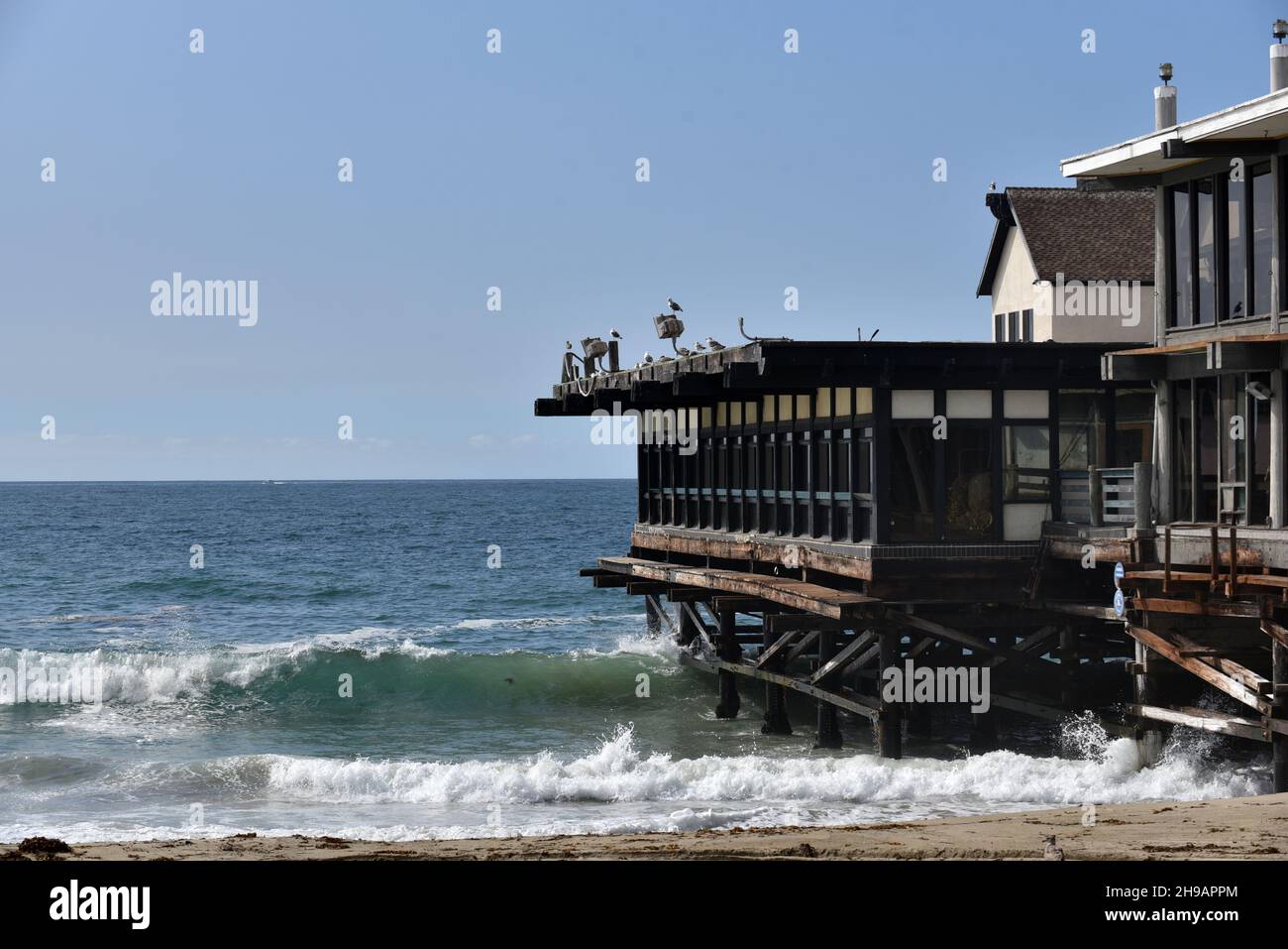 Waves breaking alongside an old rustic pier at a tropical resort Stock Photo