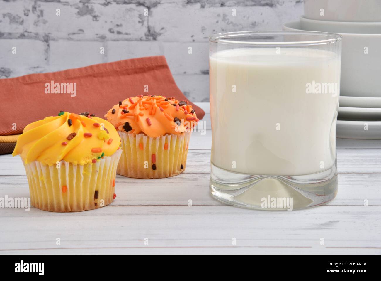 Colorful holiday cupcakes with a glass of milk on a rustic white wooden table Stock Photo