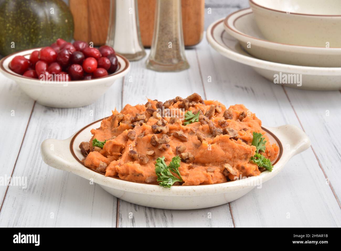 A bowl of sweet potatoes with glazed pecans on a holiday table Stock Photo