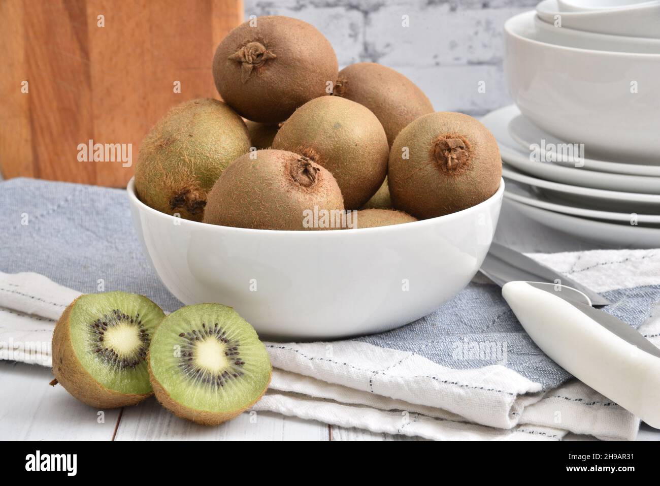 A bowl of fresh kiwi on a white wooden kitchen countertop Stock Photo