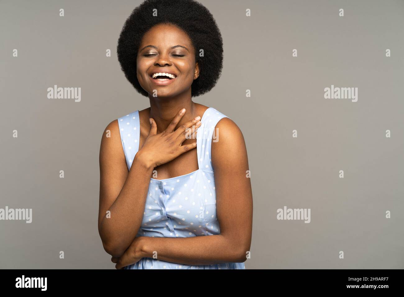 Cheerful african woman in blue dress happy laughing. Delightful young girl smiling with closed eyes Stock Photo
