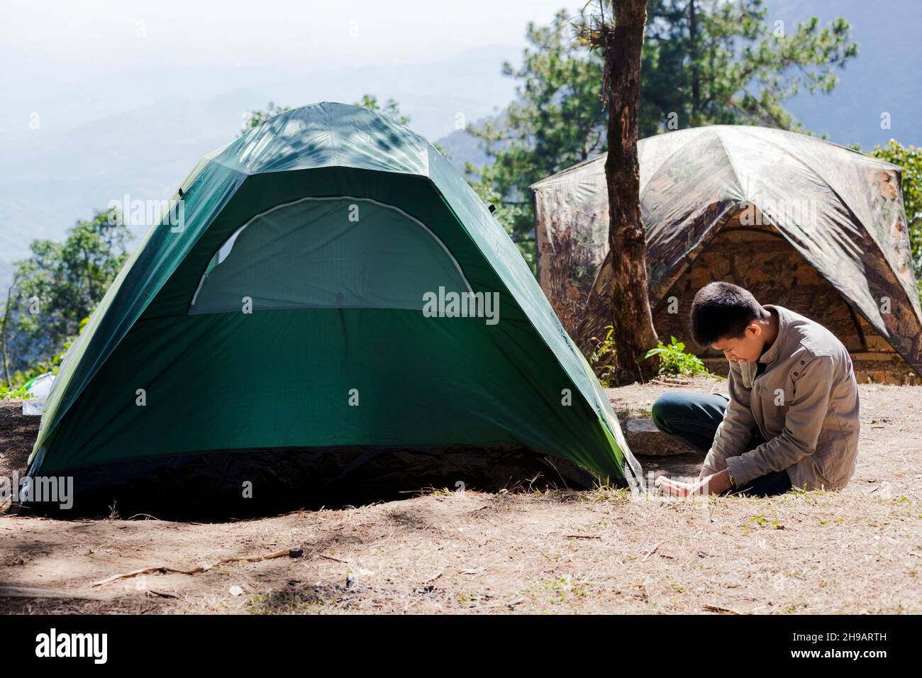 A man pitching a tent in mountain Stock Photo