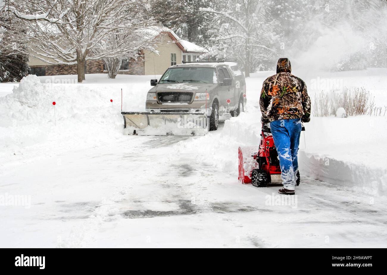 a team with a snow plow and a blower work hard to clear driveways as