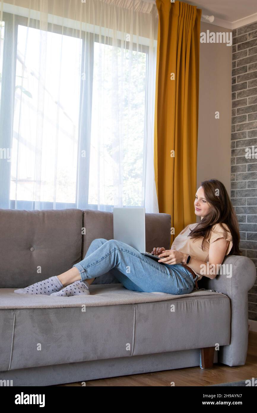 Comfortable work from home. A young woman is working remotely with a laptop. Stock Photo