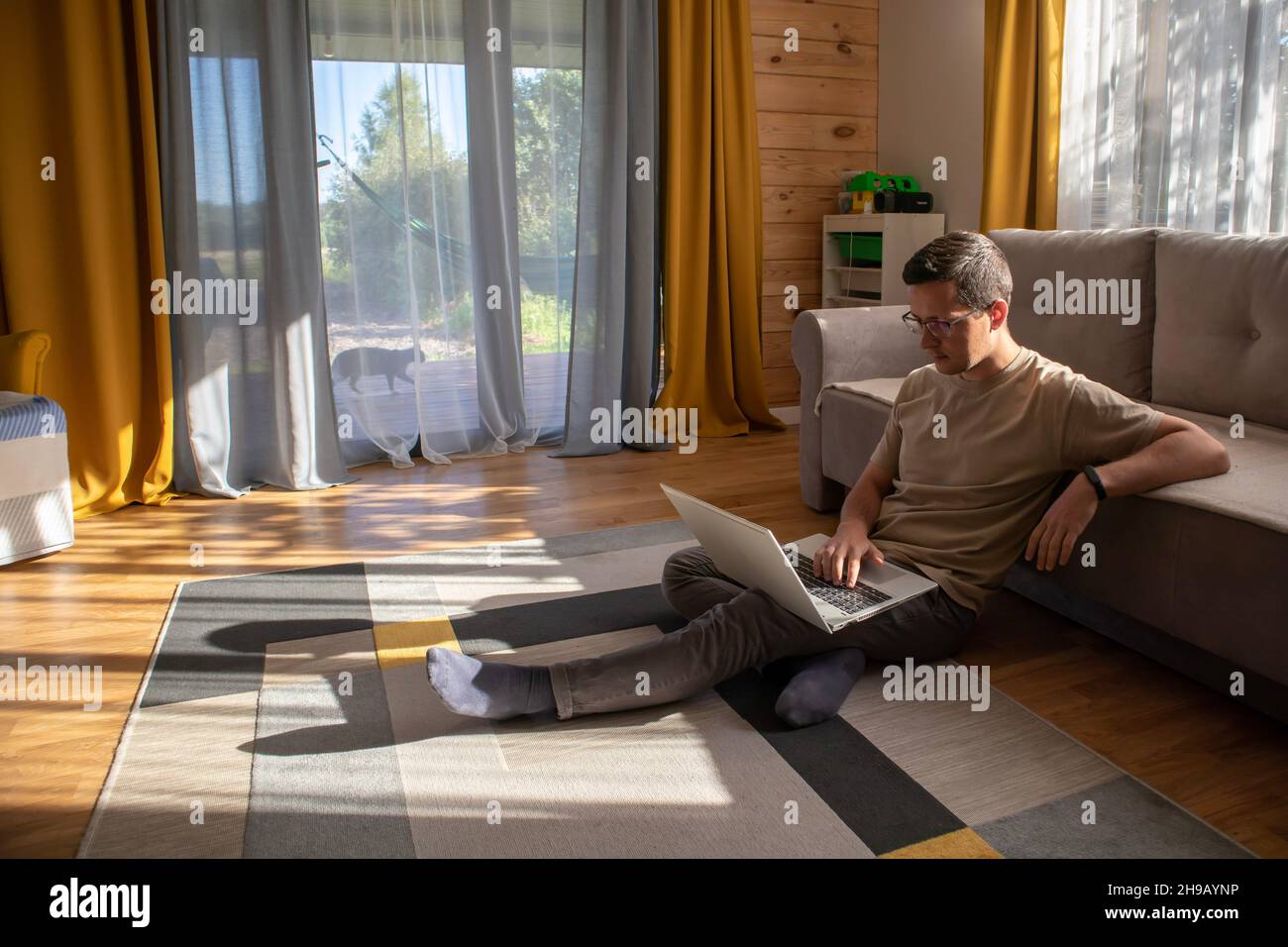 Home office in a sunny loft apartment. Man sitting on the floor and working Stock Photo