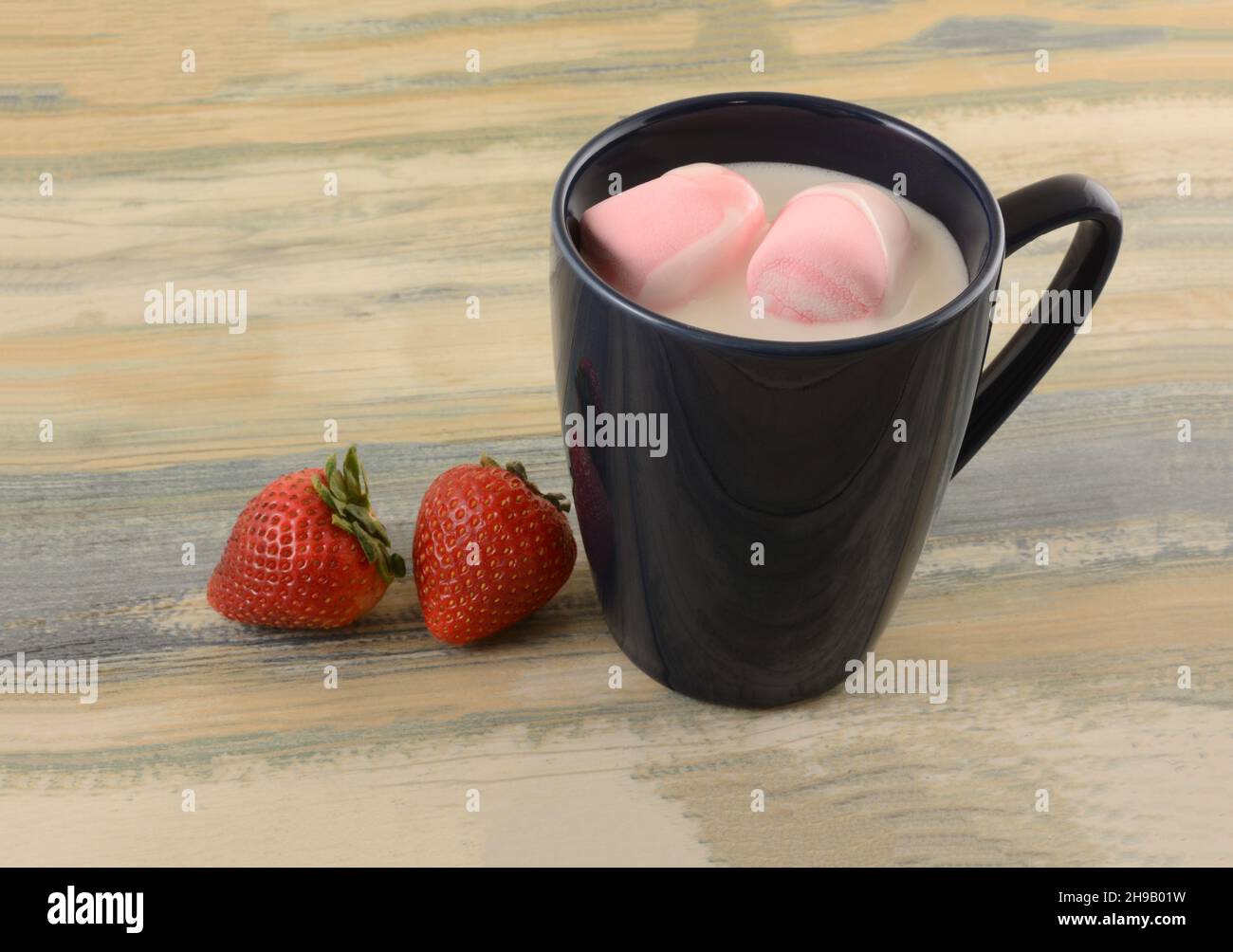 Hot white chocolate with pink strawberry marshmallows in blue mug with fresh strawberries Stock Photo