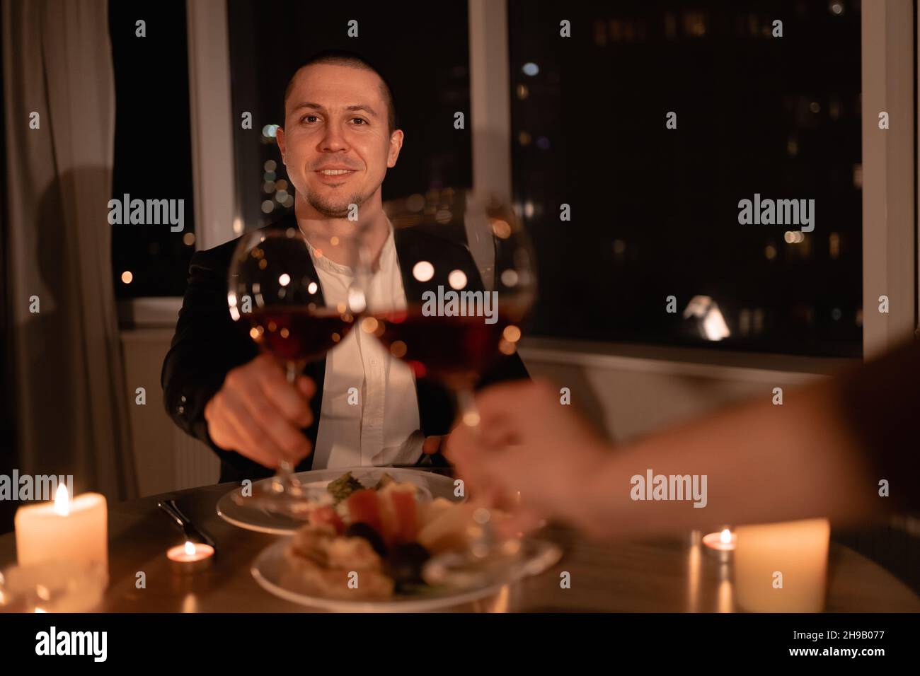 dinner valentines day, couple hands with glass of wine, evening of love at home together, date after work, wedding anniversary dine with alcohol Stock Photo