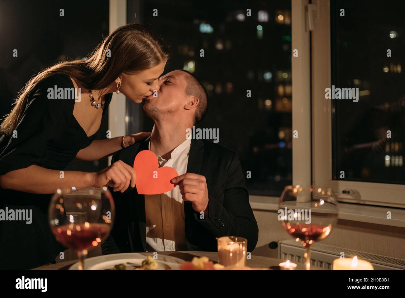 Date at night couple having dinner with candles, family celebrating valentine's day at home, wine in glasses on the table, 14 february woman in love Stock Photo