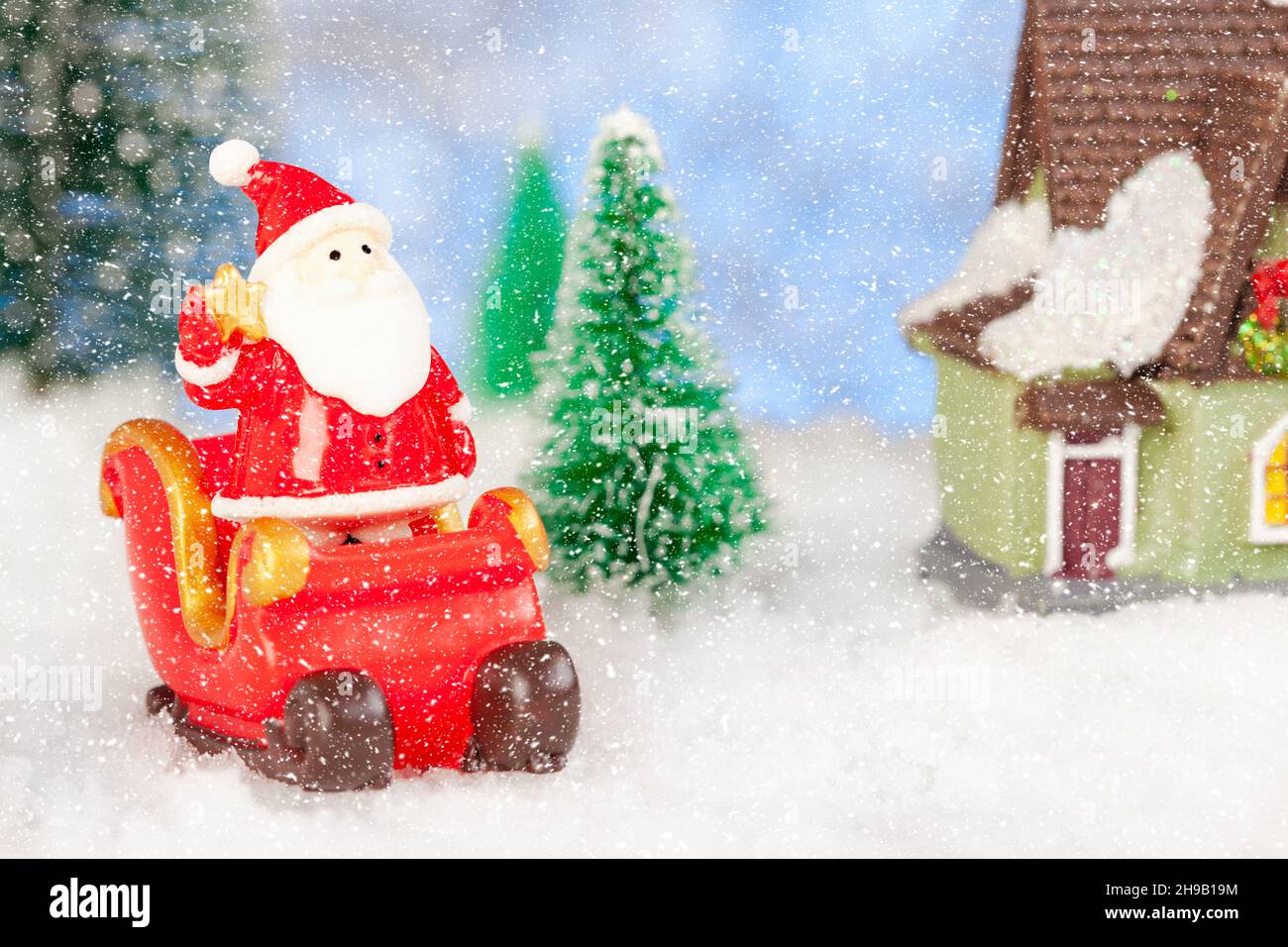 Toy santa claus and sleigh in the snow, artificial fir trees around ...