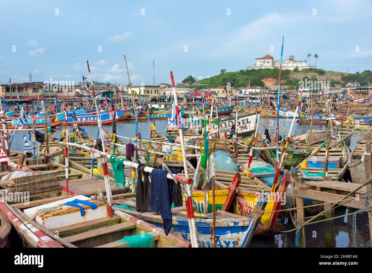 Colorful fishing boats in the harbor, Fort Coenraadsburg (Fort Sao Tiago da Mina) in the distance, Elmina, Central Region, Ghana Stock Photo