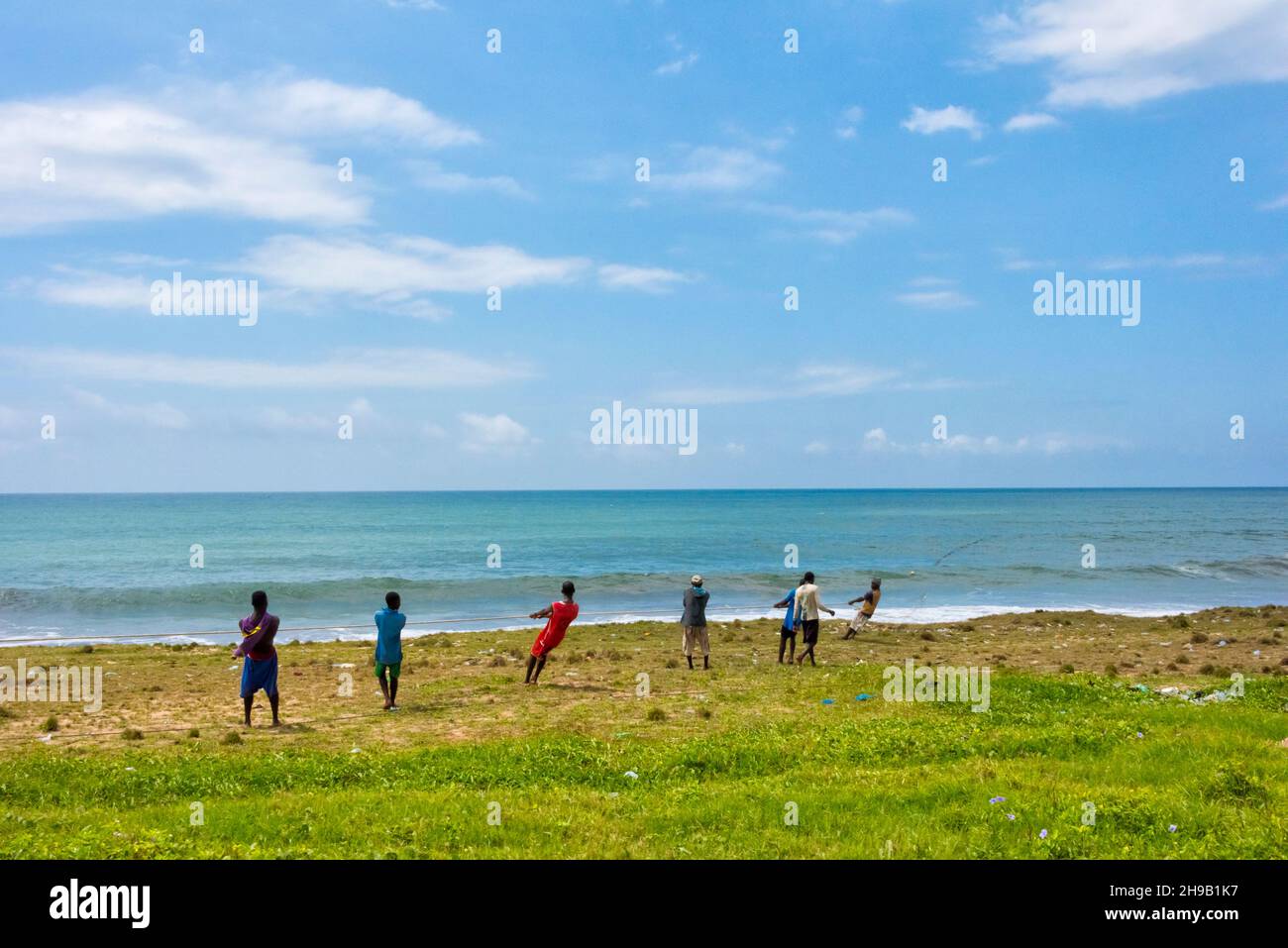Fishermen pulling in fish net on the beach, Cape Coast, Central Region ...