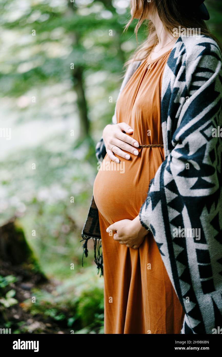 Pregnant woman hugs her belly with her hands in the park Stock Photo ...