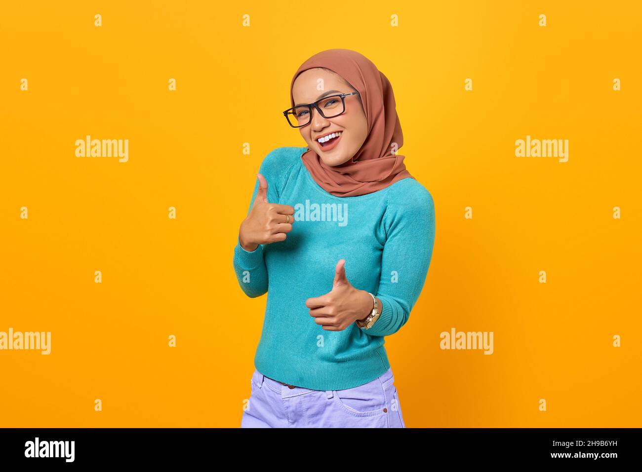 Cheerful beautiful young Asian woman showing thumbs up gesture isolated ...