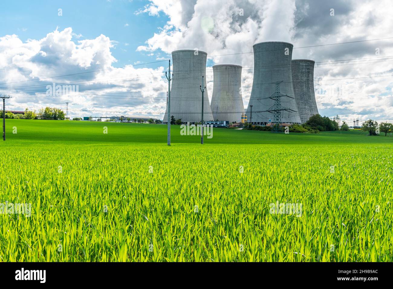 Cooling tower of nuclear power plant behind green grass. Atomic energy. Nuclear power and the environment. Stock Photo