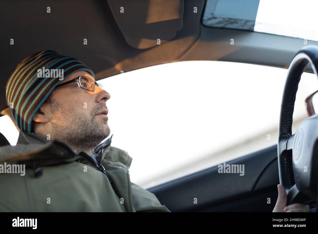 Adult man taxi driver driving car vehicle looking forward. Stock Photo